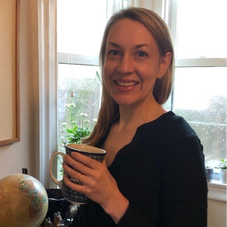 Emily Goedde holding a mug in front of a window