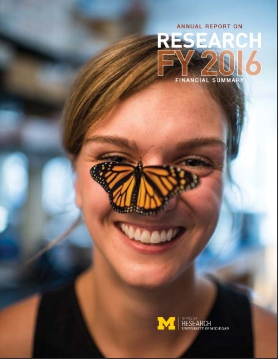 Smiling young woman with a monarch butterfly perched on the woman's nose
