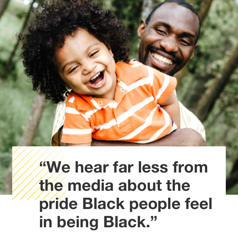 Image shows a smiling man holding a toddler who’s laughing. Pull quote text reads: We hear far less from the media about the pride Black people feel about being Black. 