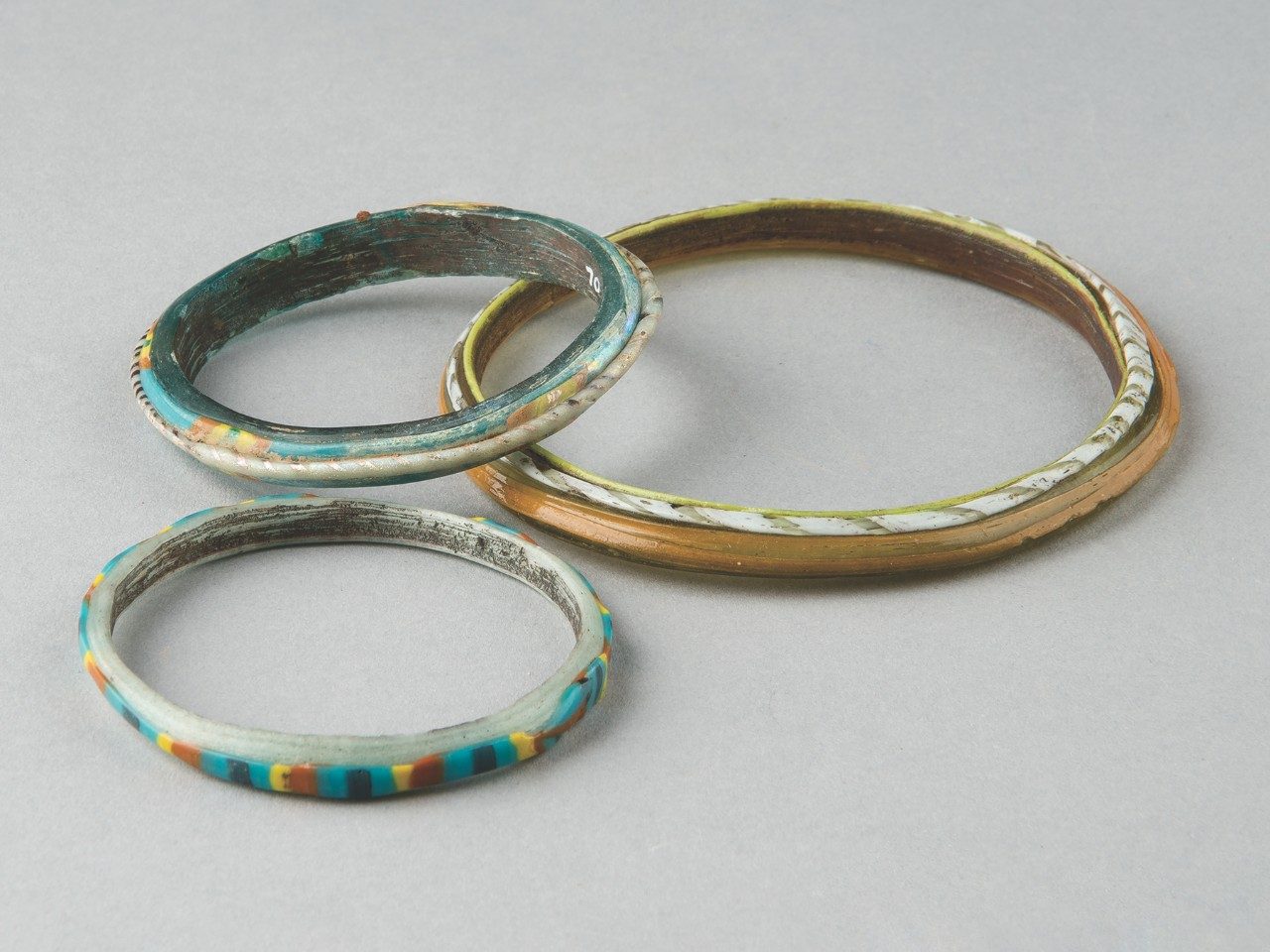 Three glass bangles with colorful geometric patterns.
