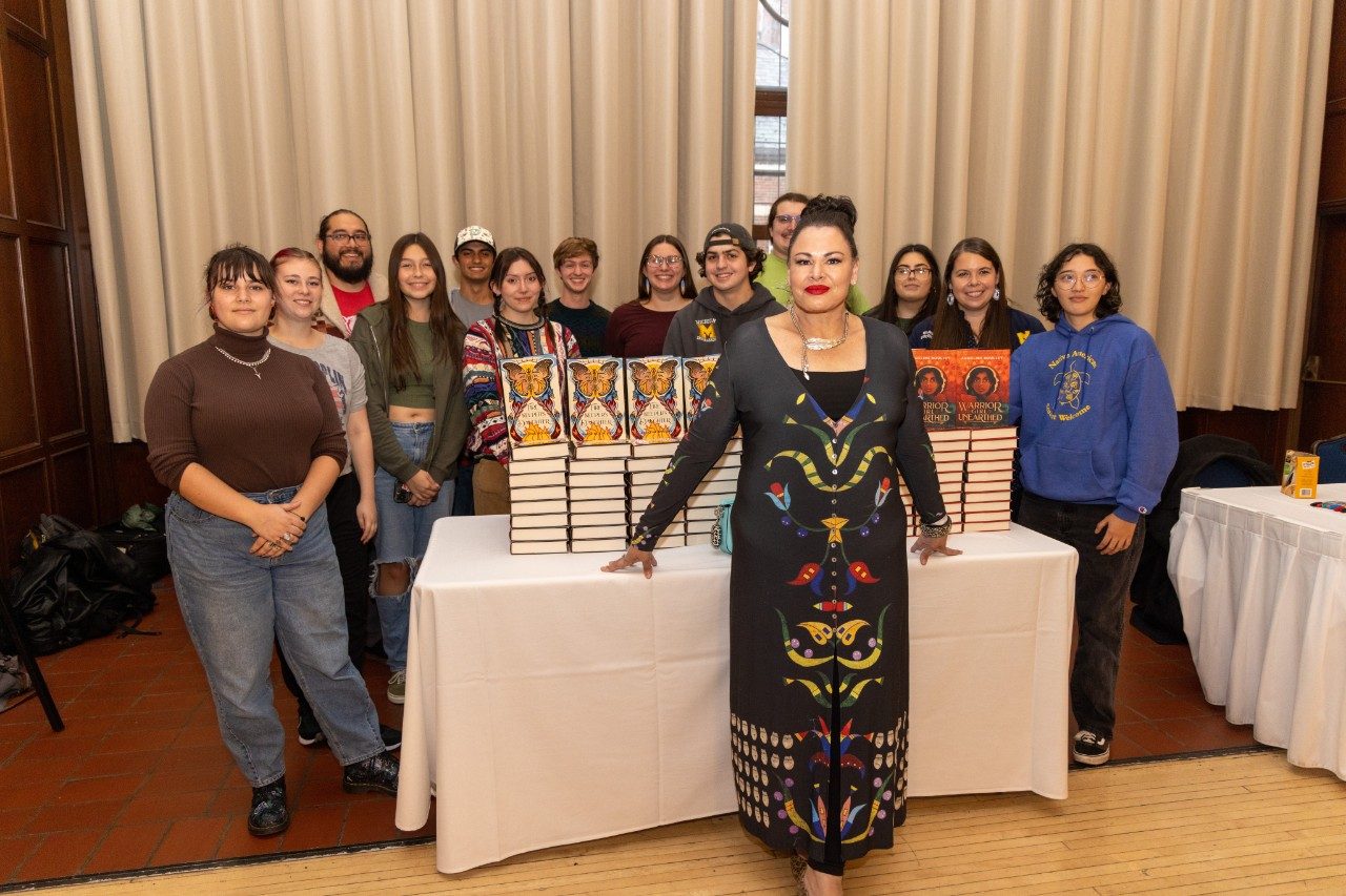 Angeline Boulley posing with students in front of the table with her books. 