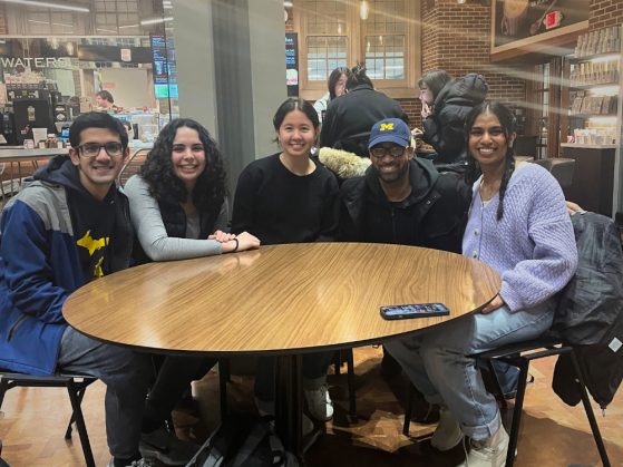Group of PCAP students and man sitting around a table smiling in a café