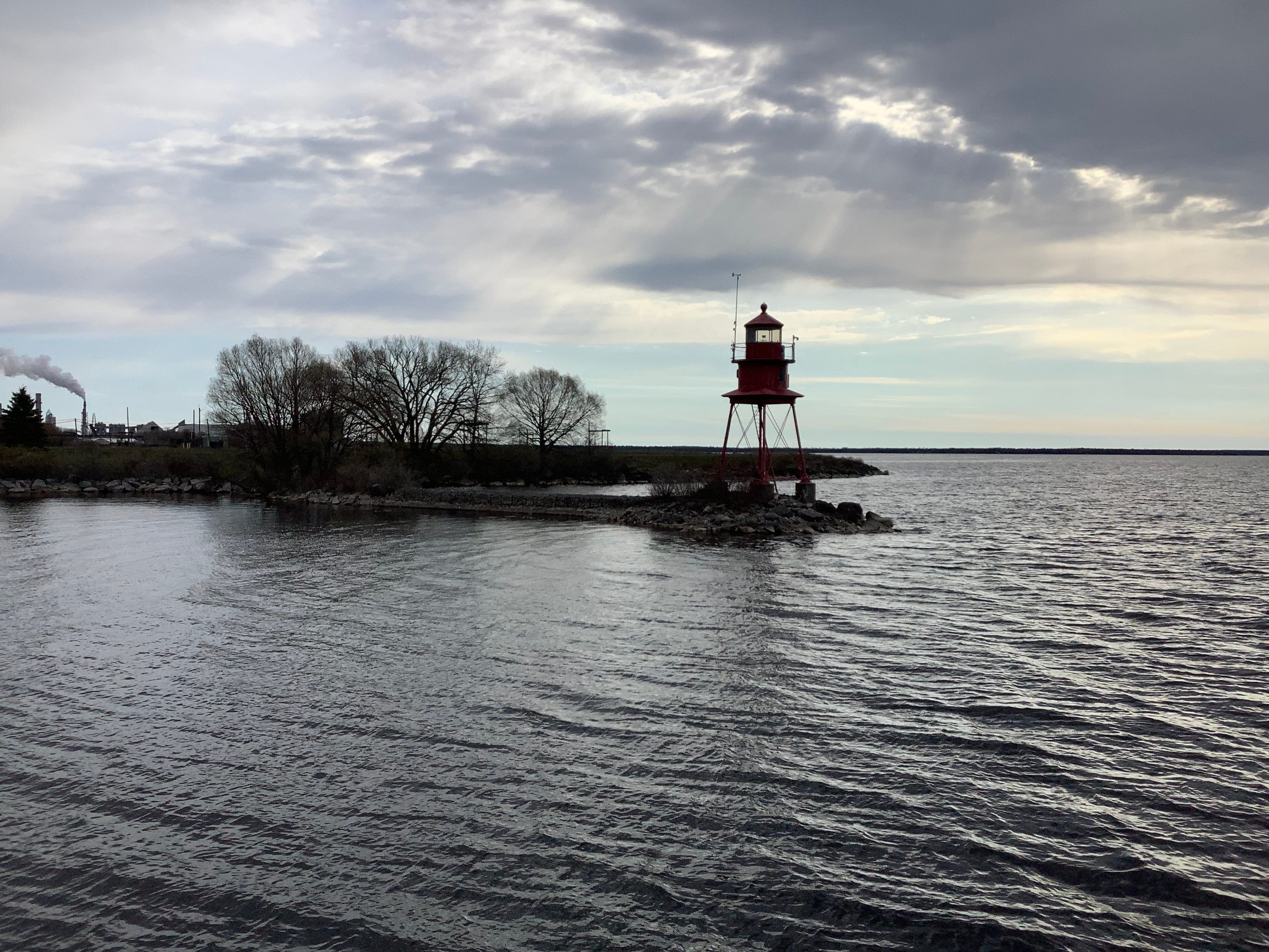 A view across Thunder Bay, with the shoreline in the distance. A red lighthouse sits at the edge of the water.