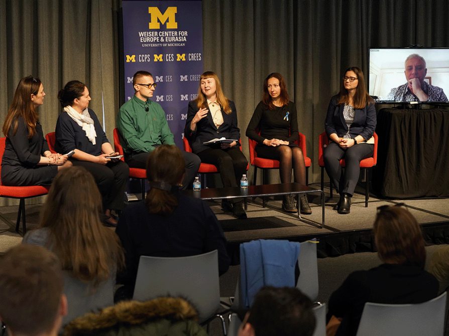 Weiser Center for Europe and Eurasia at the University of Michigan staff and fellows from Ukraine sit on stage at a panel discussion about the future of Ukrainian Academia. The six people on the panel were joined virtually by Serhiy Kvit, president of the National University of Kyiv-Mohyla Academy, who appears on a monitor at the right side of the picture.