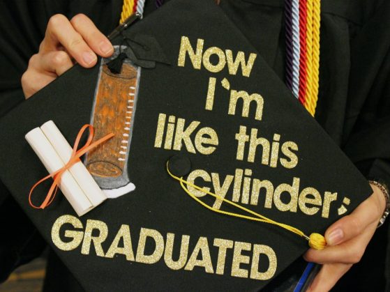 decorated mortarboard with paper scroll and graduated cylinder and words "Now I'm like this cylinder: graduated"