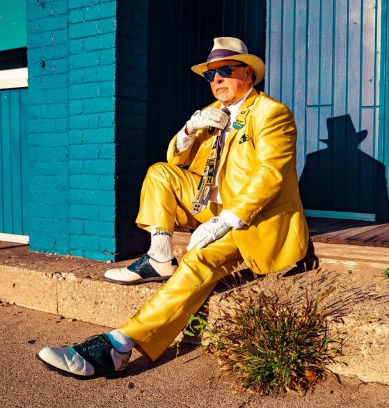 Charlie Doering wears a vibrant Maize-colored suit, tie, sunglasses, and hat, all of which are University of Michigan merchandise. 
