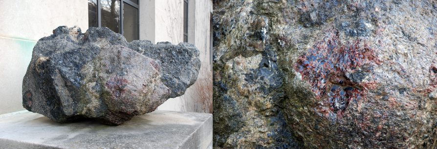 Side by side photographs: left, dark oblong rock resting on a light colored platform next to building doors, right, a close up showing red crystal structure embedded in brown and black matrix.