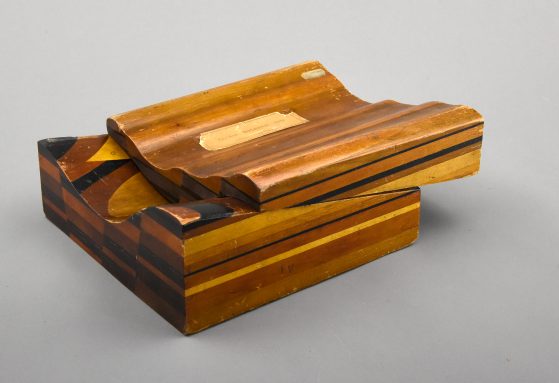 Photograph of two part model made of laminated wood, top offset from bottom, photo by Dale Austin