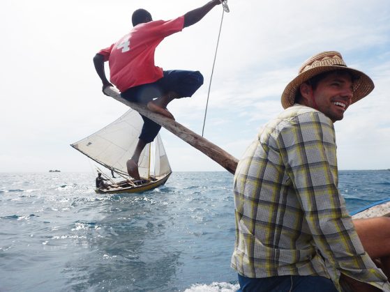 Jacob Allgeier headed to a field site in Haiti to build artificial reefs. He's on a boat with another researcher and another sailboat is in view
