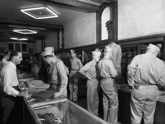 A black-and-white photo of men in military uniform who are browsing through the clothing store Van Boven.