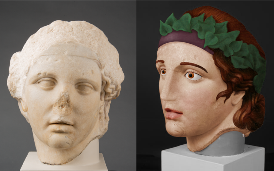Two busts; one is the typical pale white color and has a broken nose. Next to it is a bust that is colored -- skin, the eyes, the lips, etc. There is a laurel wreath in the hair.
