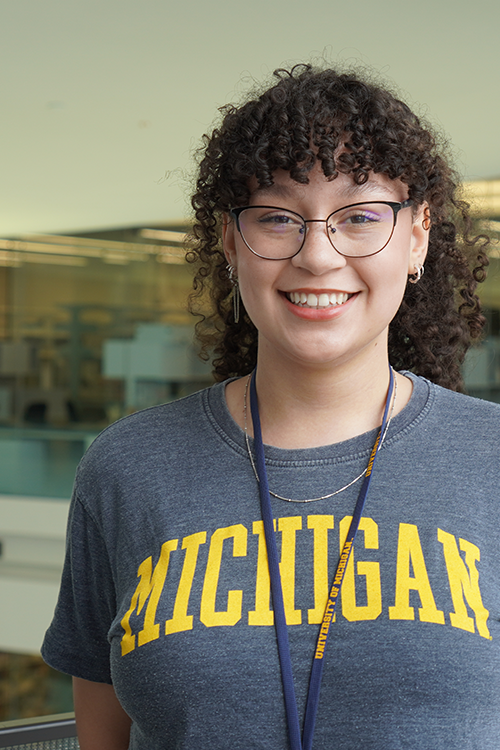 Sydney Richard, wearing a blue University of Michigan t-shirt, smiles into the camera.