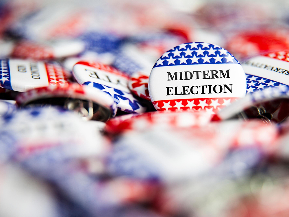 Red, white, and blue election pins, with one in the foreground that says, "Midterm Election." 