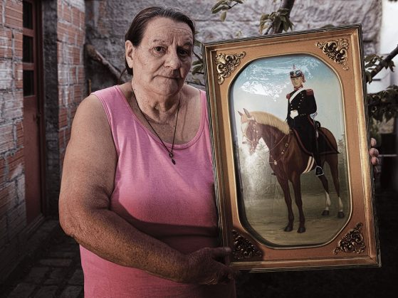 Photograph of Catalina Dickason holding a portrait of her ancestor on horseback.