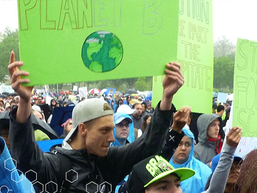 Man standing in the crowd at the Science March holding up a green sign that says Planet B