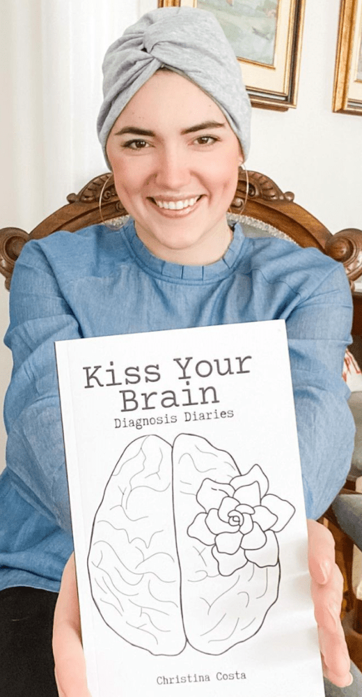 A photograph of Christina Costa holding her book, “Kiss Your Brain.”