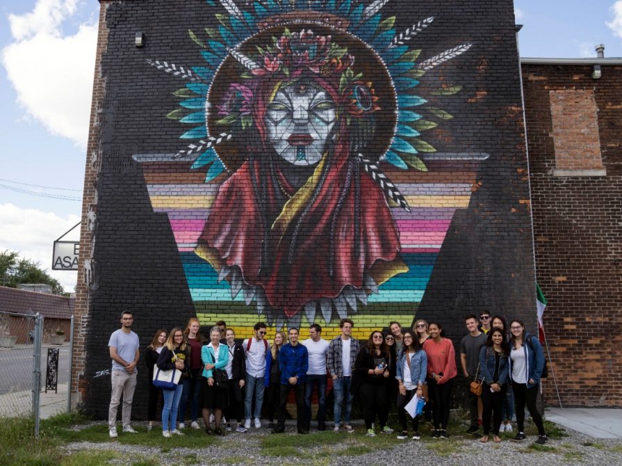 In Detroit's Mexicantown, History 328 pose in front of a Victor Quiñonez (aka Marka27) mural. (Photo: Marian Krzyzowski)