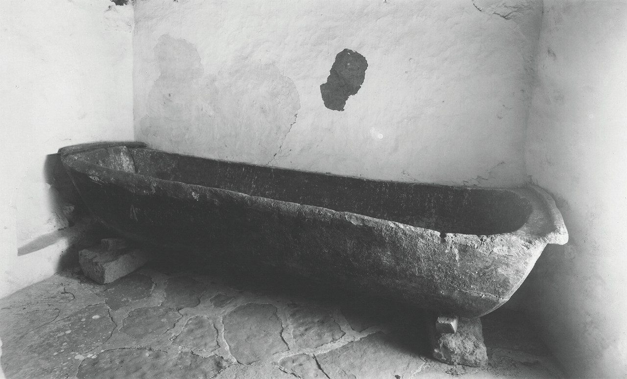 A long, roughly hewn, stone trough rests atop wood and stone supports.