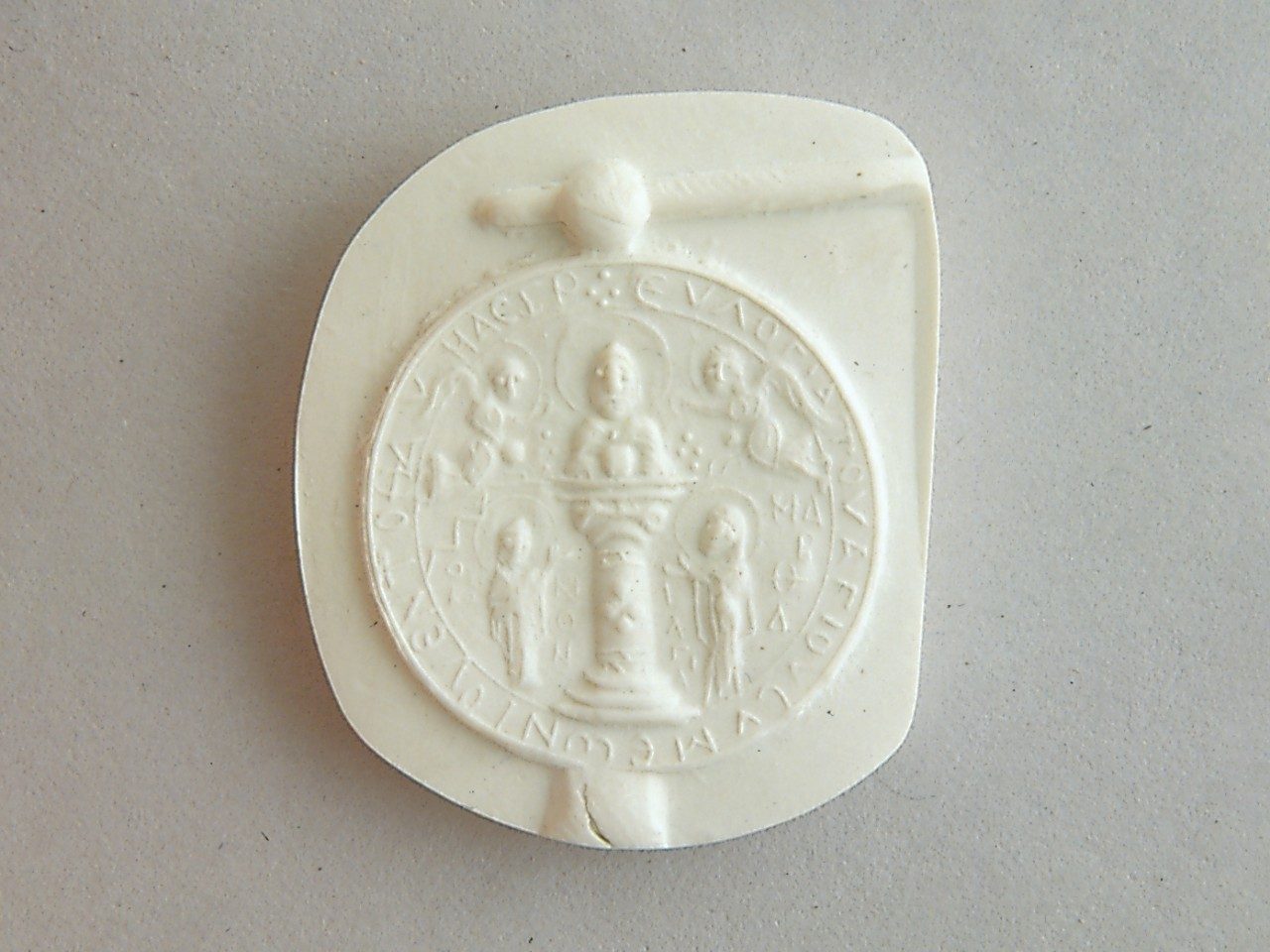 White steatite mold with a raised pattern featuring a monk (Simeon), angels, and two human figures flanking him.