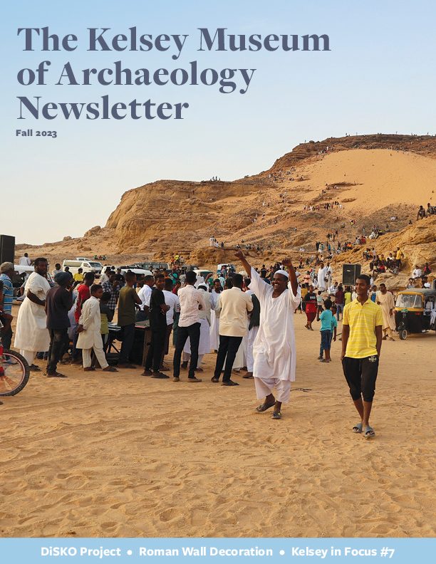 Cover of the Fall 2023 edition of the Kelsey Museum Newsletter, featuring crowds of people and cars at Jebel Barkal, Sudan.