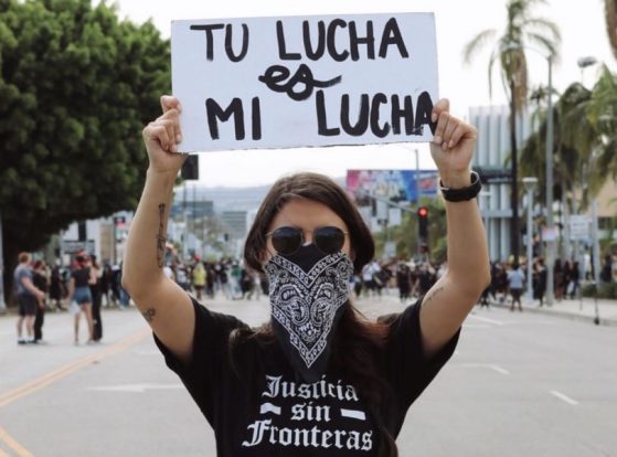 Protester Holding Sign: Tu Lucha es Mi Lucha