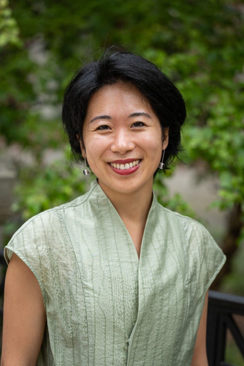 Color headshot photo of Carlina Duan with green leaves in the background