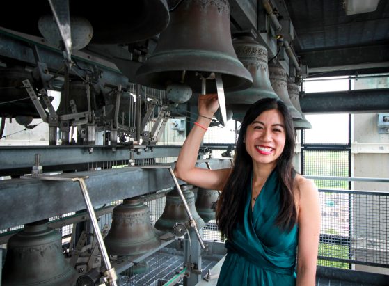 Tiffany Ng posing with the University of Michigan carillon (bell tower bells)