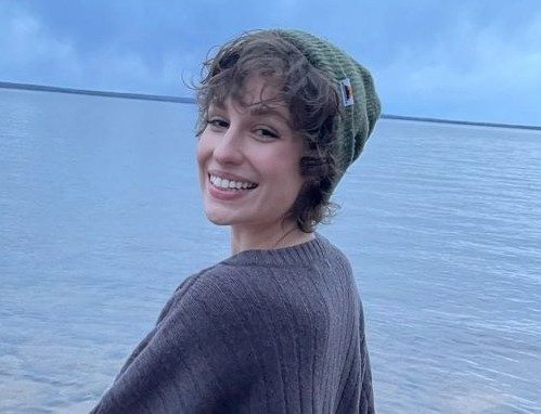 Chloe smiling with knit cap on by lake