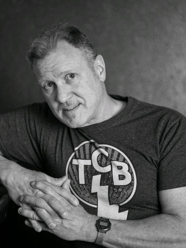 Black and white portrait of man with TCB on his t-shirt