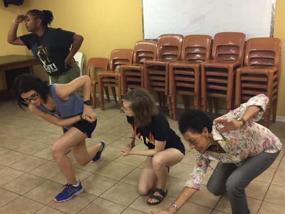four people stand, lean down, and squat during a theatre excercise