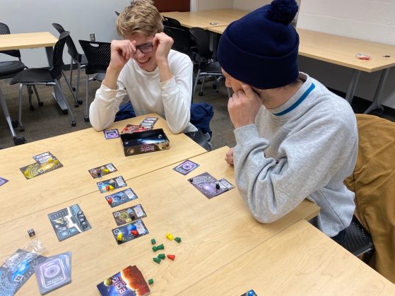 two students laugh over the game Tiny Epic Galaxies