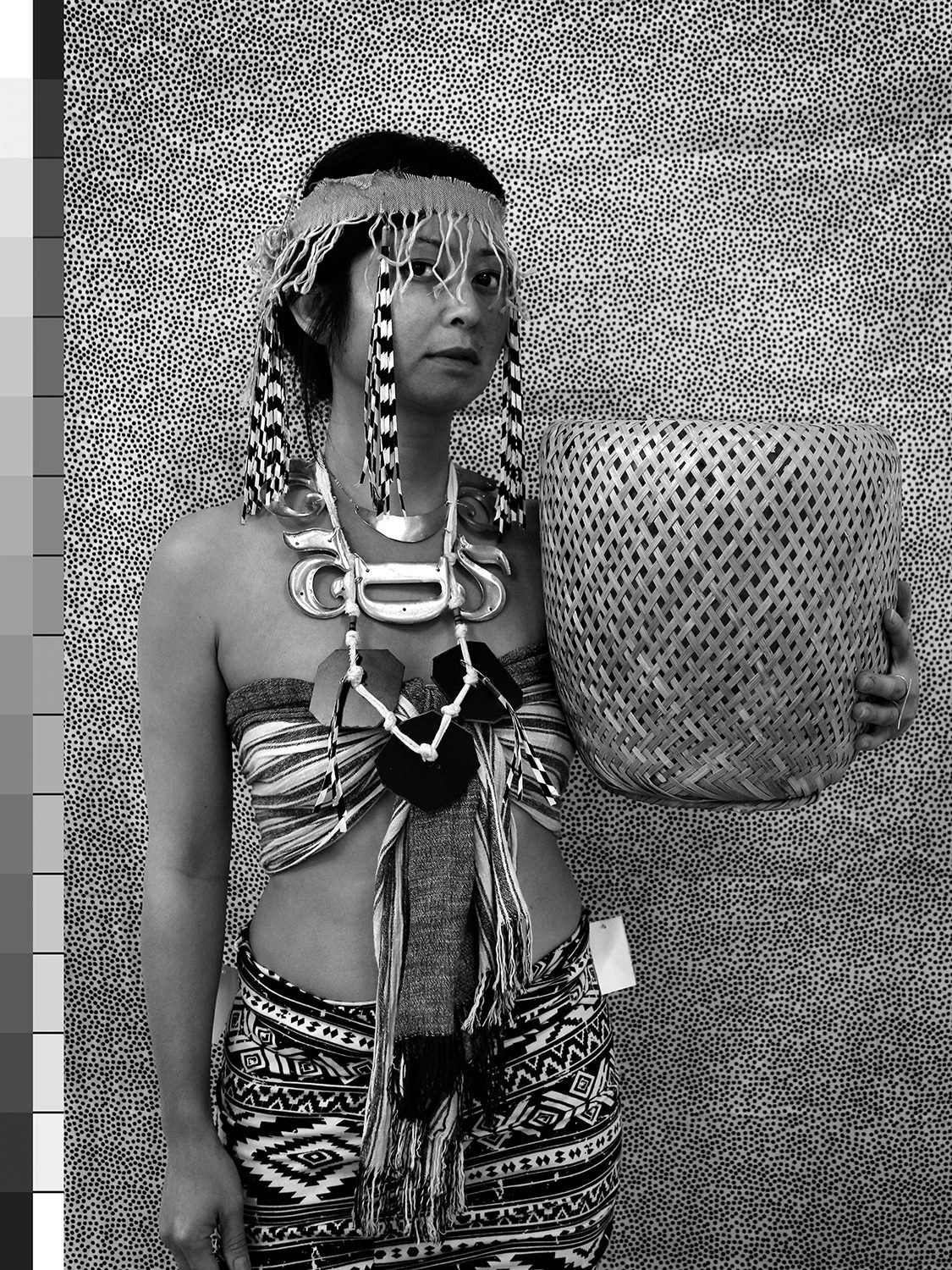 Woman holding a basket in indigenous dress looking at the viewer with a price tag in black and white