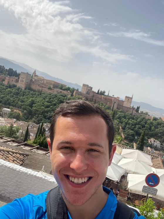 Image of undergraduate student Lucas Rubin (Spanish Major); a selfie taken while abroad in Granada, Spain. The Alhambra palace-city can be seen in the background.