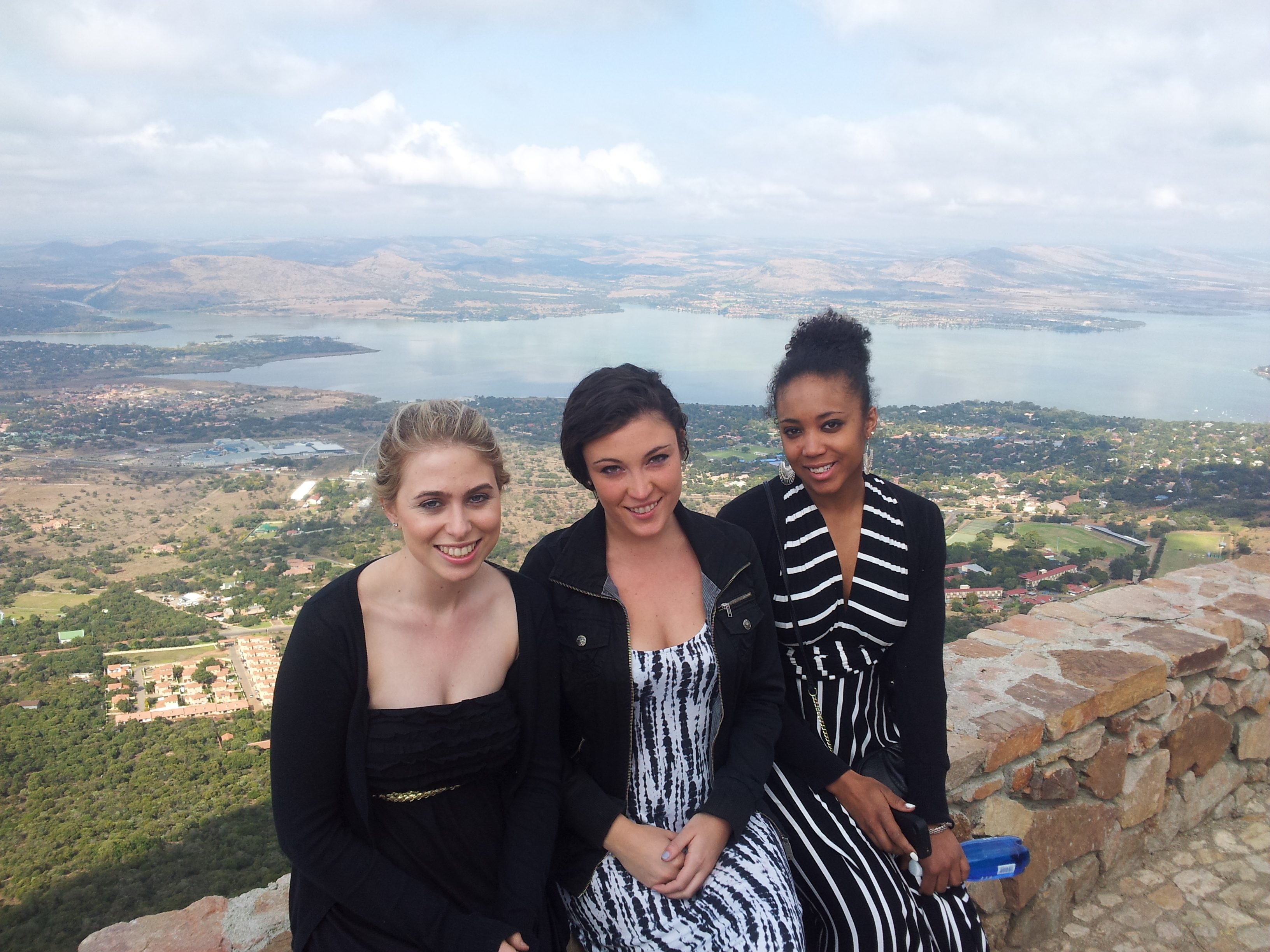 Three female sociology students sitting shoulder to shoulder with South African landscape in background
