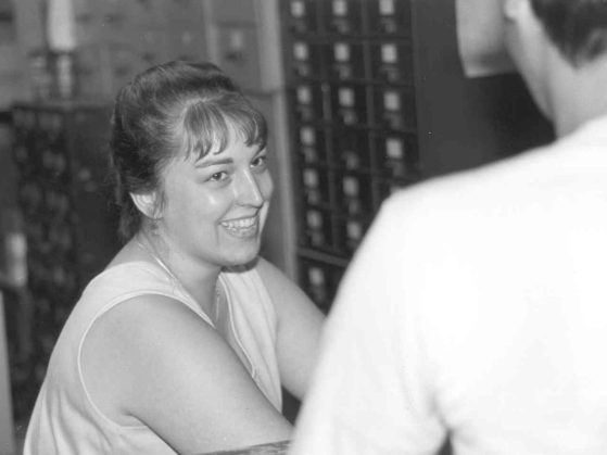 A black and white photo of Lisa Readmond smiling while working in the UMBS stock room. 