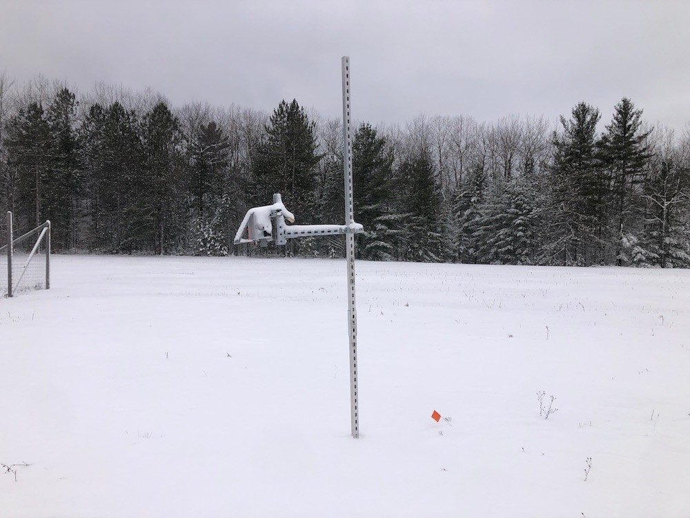 Scientific device mounted on a pole in a snowy forest