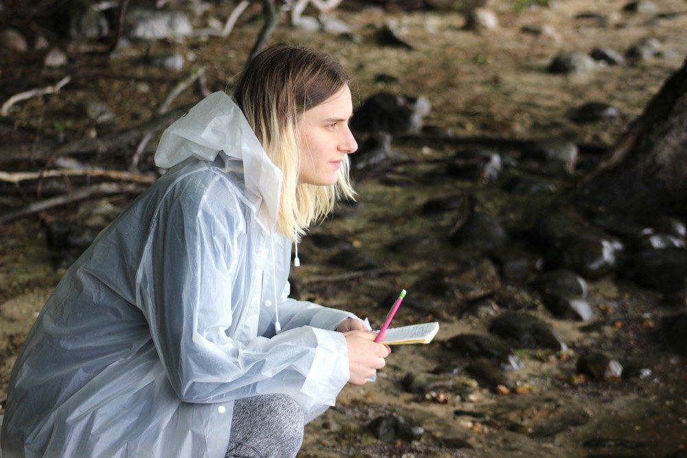 Person on shore with notebook and pencil