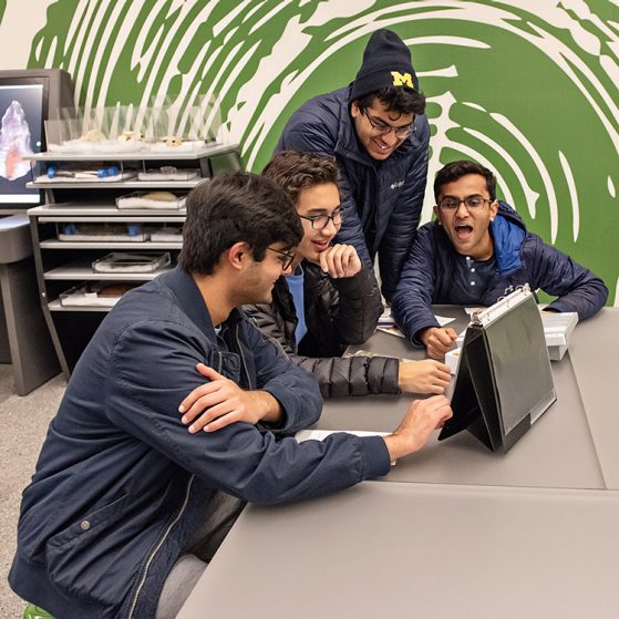 Group of 4 students looking at ipad in lab