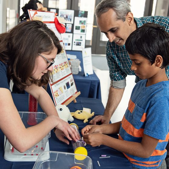 Scientist demonstrating research to adult and child